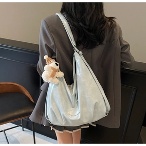 Détail d'un sac cabas en similicuir bleu clair avec un joli porte-clés ours en peluche
