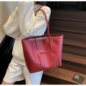Detail of red oversized tote bag with front zipper pocket on a model with white clothes