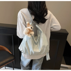 Sac fourre-tout bleu clair en similicuir avec charm ours porté par une personne en tenue décontractée