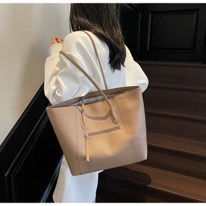 Detail of khaki tote bag featuring premium leather texture and front metal zipper pocket