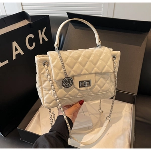 Detail of white quilted handbag with silver chain strap and metal rotary lock clasp