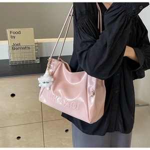 Detail of pink faux leather tote bag with logo embossing and a white plush keychain