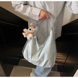 Détail macro du sac cabas en cuir souple bleu clair avec pendentif ours en peluche