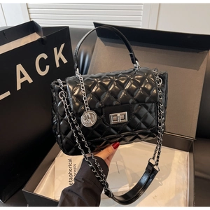 Detail of glossy quilted crossbody bag with silver chain strap and metal lock closure