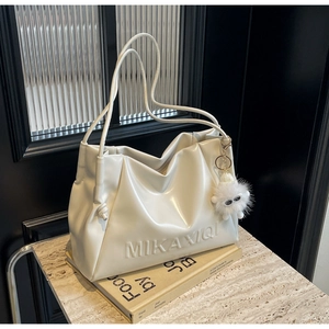 Close-up of white soft leather tote bag with embossed lettering and furry charm
