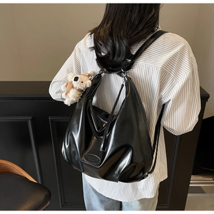 Sac à dos en cuir noir brillant en forme de croissant porté par un mannequin avec ours