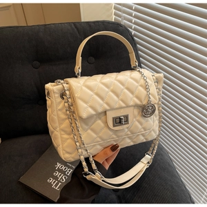 Detailed view of beige quilted handbag with silver clasp and elegant chain strap texture