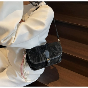 Nahaufnahme einer schwarzen Falten-Schultertasche mit goldener Schnalle und Knotendekor