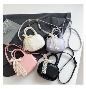 Flat lay of four mini crossbody bags with lace bows in white, lilac, pink and black colors