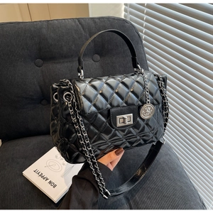 Detail shot of black quilted leather handbag with silver chain strap and twist lock