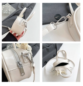 Macro detail of creamy white leather crossbody bag with silver hardware and lace bow charm