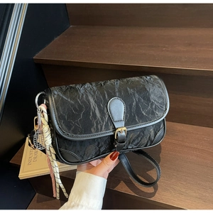 Detail der schwarzen Tasche aus Faltenleder mit Metallschnalle und Tennis-Anhänger-Zubehör