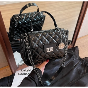 Close-up of black quilted leather handbag with silver chain and metallic turn-lock