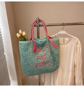 Detail of mint green straw tote bag with pink SWIM AND TONIC embroidery and tassels