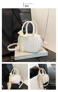 Detailed close-up of white PU leather square bag with lace bow accessory and top handles