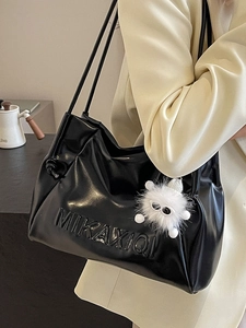 Minimalist black faux leather tote bag with embossed letters and plush charm pendant