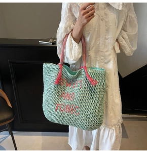 Detail of mint green woven tote with pink Swim and Tonic embroidery and tassel handle