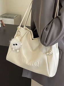 Minimalist creamy white leather tote bag with embossed letters and plush monster charm
