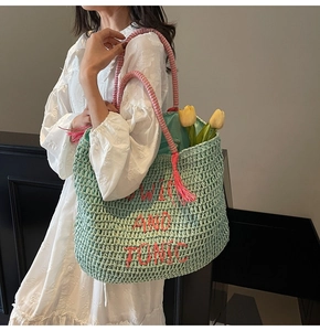 Detailed macro view of mint green straw tote bag with red Gin and Tonic embroidery and pink tassels