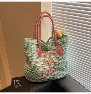 Close-up of mint green hand-woven straw tote bag with pink Swim and Tonic embroidery