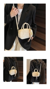 Detail der cremefarbenen Mini-Tasche mit Blumenprägung, Quastenanhänger und Golddekor