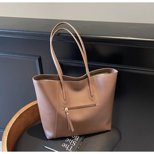 Detail of a dark brown large tote bag showing the front zipper pocket and leather texture