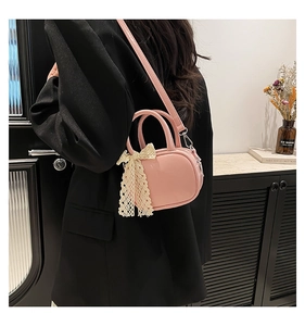 Pink mini crossbody bag with lace bow accessory worn by model in a vintage setting