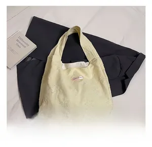Close-up of textured star pattern and pink label on beige canvas tote bag