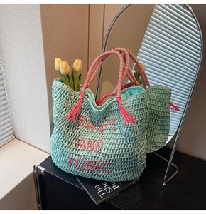 Detail of mint green straw tote bag with pink SWIM AND TONIC embroidery and tassels