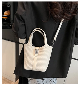 Close-up of cream white bucket bag with woven texture and silver buckle on a model