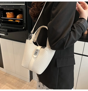 Close-up of a white woven bucket bag featuring a silver bee-shaped metal clasp and handle