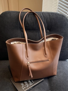 Brown minimalist high-capacity tote bag with contrast stitching on a corduroy sofa