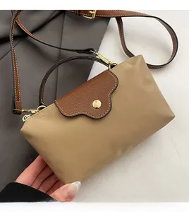 Detail of khaki nylon bag with brown leather flap and golden hardware on grey suit