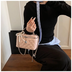 Pink quilted box bag with pearl bow detail and chain strap shown in a hand-held view