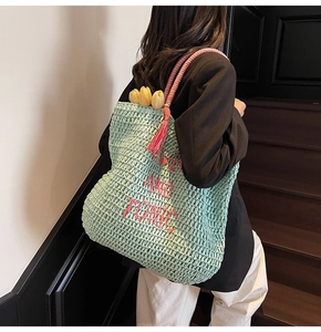 Detail of mint green woven bag with pink GIN AND TONIC embroidery and tassel