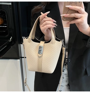 Close-up of beige woven bucket bag featuring a silver metal twist lock and leather trim