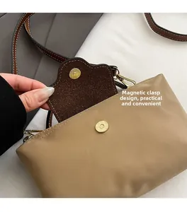 Detail of magnetic snap closure on khaki nylon crossbody bag with brown leather trim