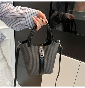 Detailed view of women's bucket bag with silver metal lock and textured fabric finish