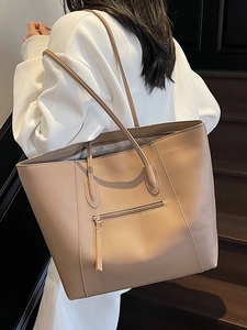Brown large capacity faux leather tote bag with front zipper pocket shown on shoulder