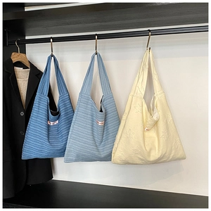 Detailed close-up of knitted tote bags with star patterns and striped patterns on hangers