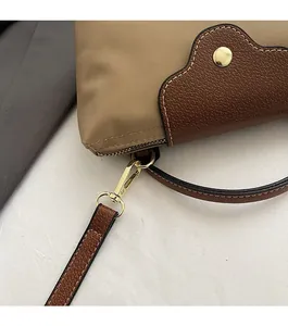 Detail of high-density nylon body with brown pebble leather trim and gold metal snap button