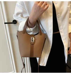 Close-up of brown woven bucket bag featuring leather trim and a silver metal turn-lock