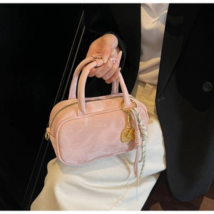 Detailansicht der rosa Handtasche mit Schmetterlings-Blumenprägung und dekorativem Anhänger