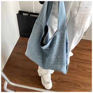 Blue knit tote bag with rib texture shown on shoulder for a casual everyday look