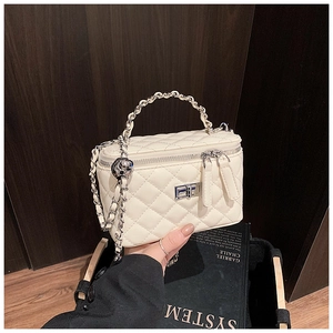 Detail of white quilted mini handbag with silver zipper and metal chain handle