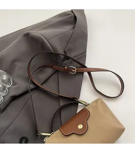 Detail of adjustable leather strap with golden metal hardware on a two-tone crossbody bag