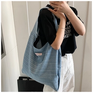 Detail view of light blue corduroy tote bag with ribbed texture and pink side label