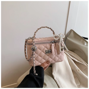 Detail of pink quilted box bag with pearl bow, heart charms and woven chain handle