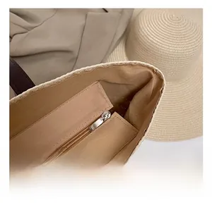 Detail shot of the beige straw bag featuring a high-quality silver metal zipper closure