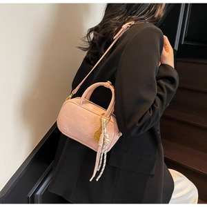 Detail der rosa geprägten Handtasche mit Schmetterlingsmustern und goldenem Quastenanhänger